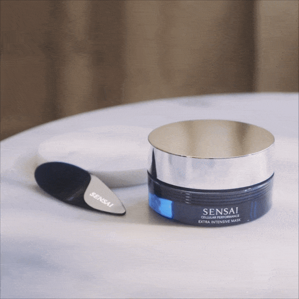 Packshot di Cellular Performance Extra Intensive Mask di SENSAI con spatola seguito da un primo piano del prodotto prelevato dal flacone con la spatola 